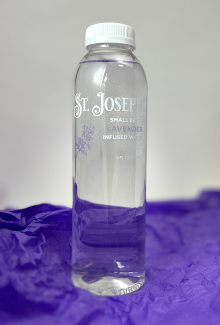 Bottle of St. Joseph Lavender infused water on a purple backdrop