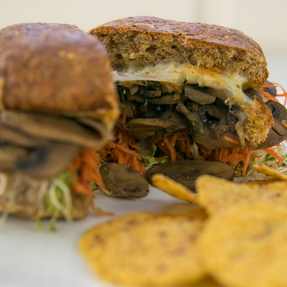 Mushroom burger on a whole wheat bun with sauteed mushrooms, avocado and sprouts